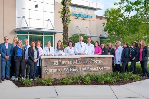 A group of doctors standing in front of a sign

Description automatically generated